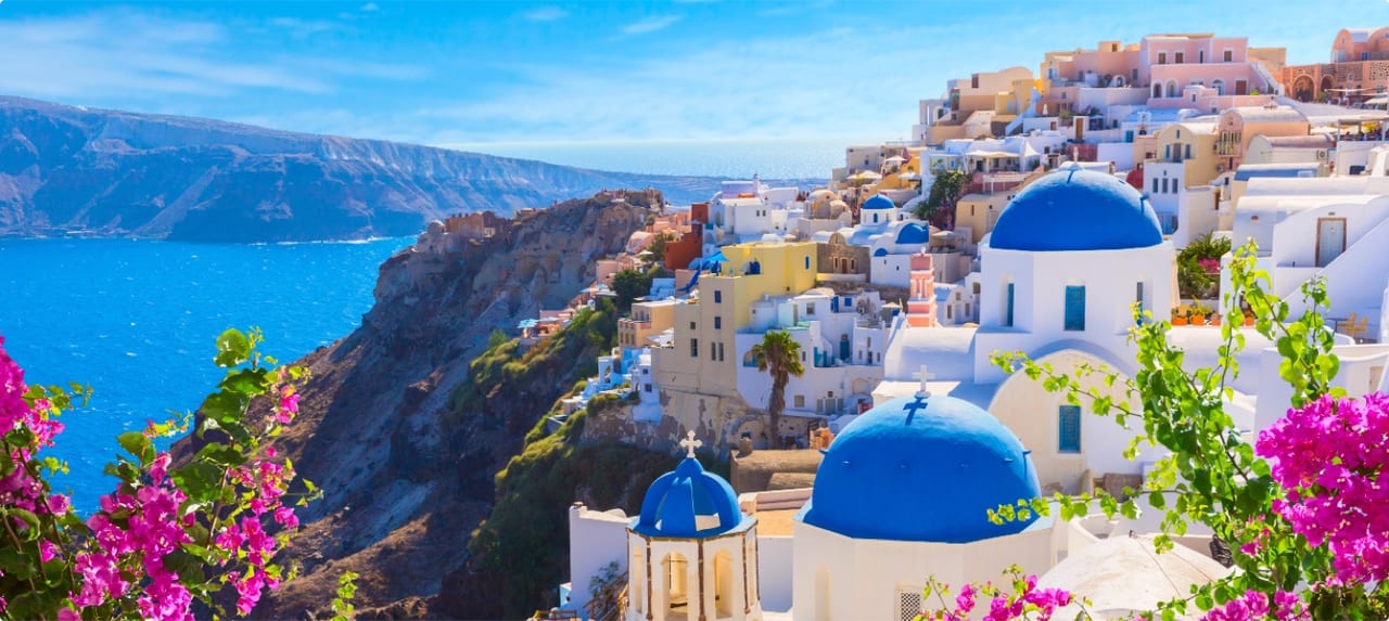 Whitewashed Greek Orthodox church with blue dome overlooking the caldera in Santorini at golden hour
