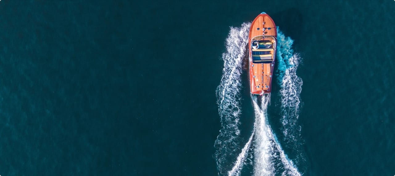 Luxury motor yacht cruising past the rugged Italian coastline on a clear Mediterranean day