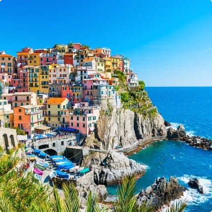 Colorful houses of Positano cascading down steep cliffs to the Amalfi Coast shoreline with boats dotting the bay