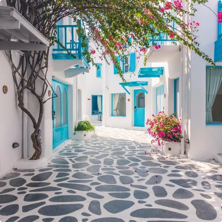 Traditional white-and-blue Greek village perched above a sparkling bay with sailing boats at anchor